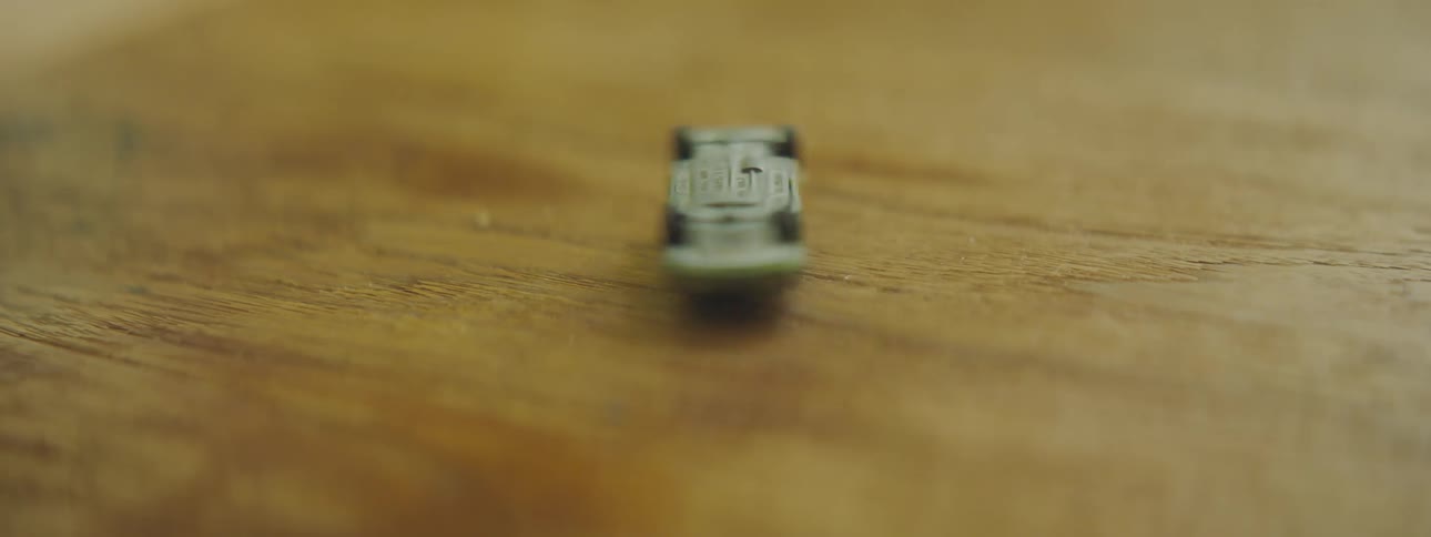 A person spinning a toy car on a wooden surface