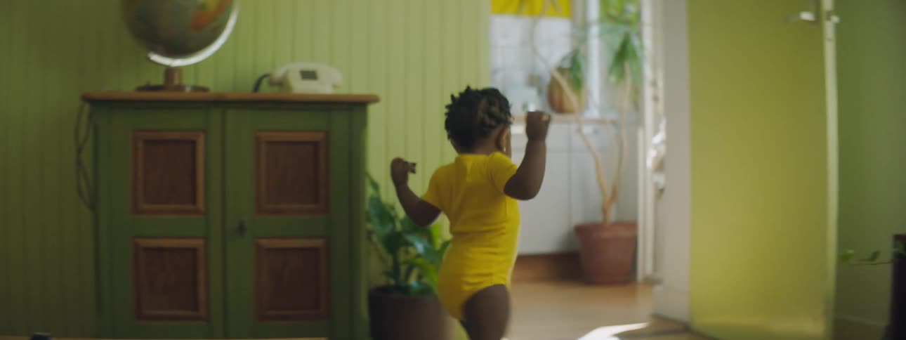 Toddler girl with yellow clothes wanders around in the living room