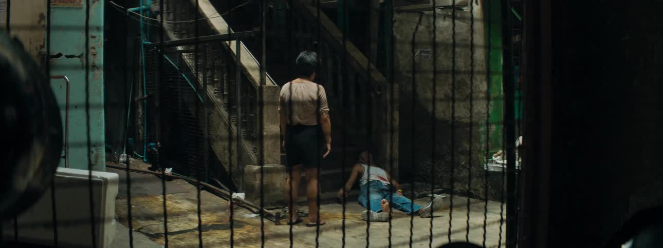 A woman standing and staring at a man laying and bleeding at the bottom of a staircase