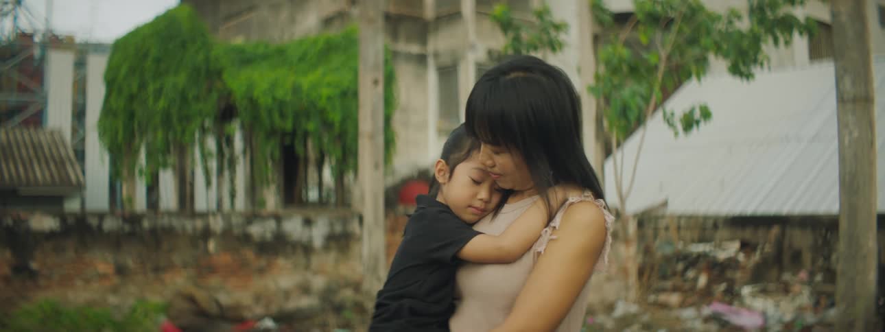 A young woman holds her daughter and rocks her outside in a neighborhood