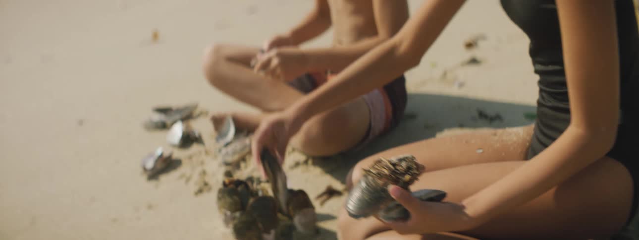 Two children stack shells on the ground