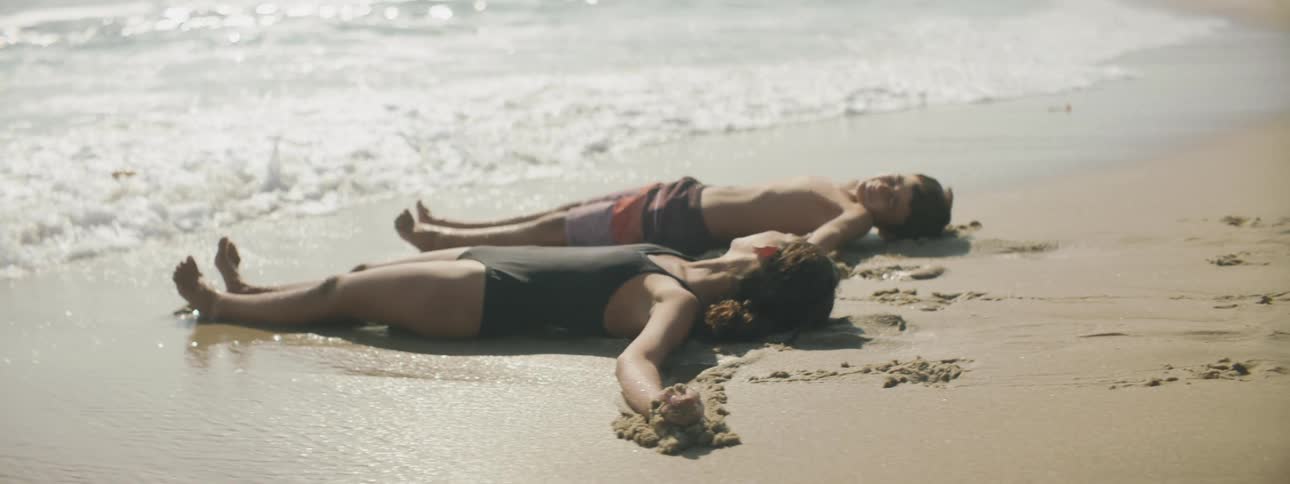 Two children lay in the sand together