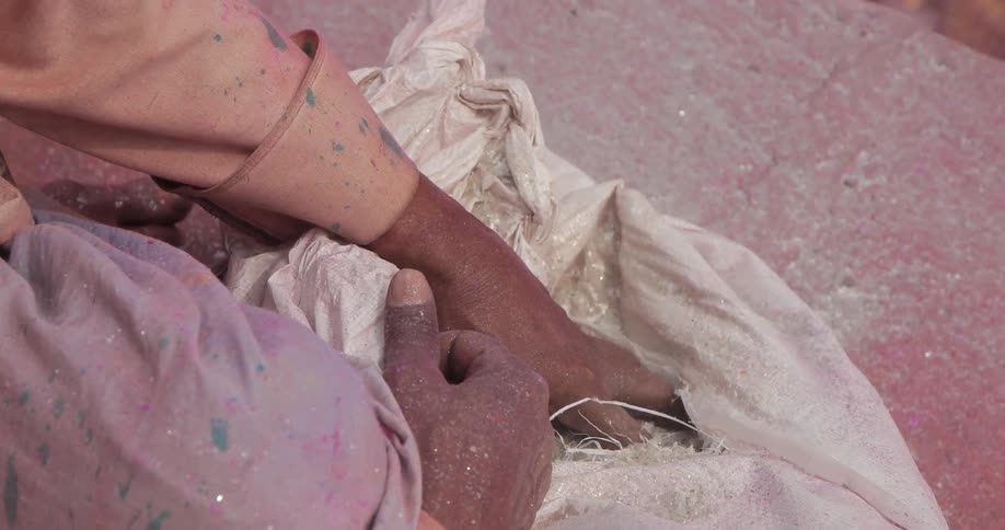 Hands scoop white dirt out of a bag