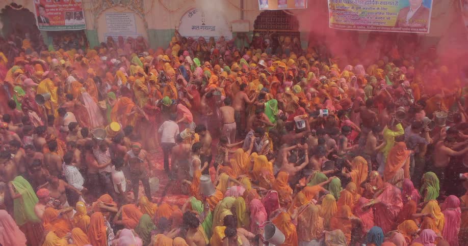 People toss colored dirt over a crowd below