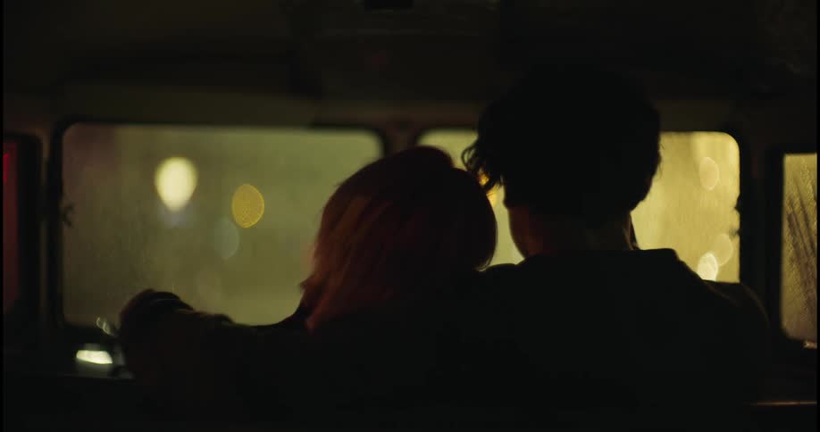 A man sits with his arm around a woman as she leans her head on his shoulder