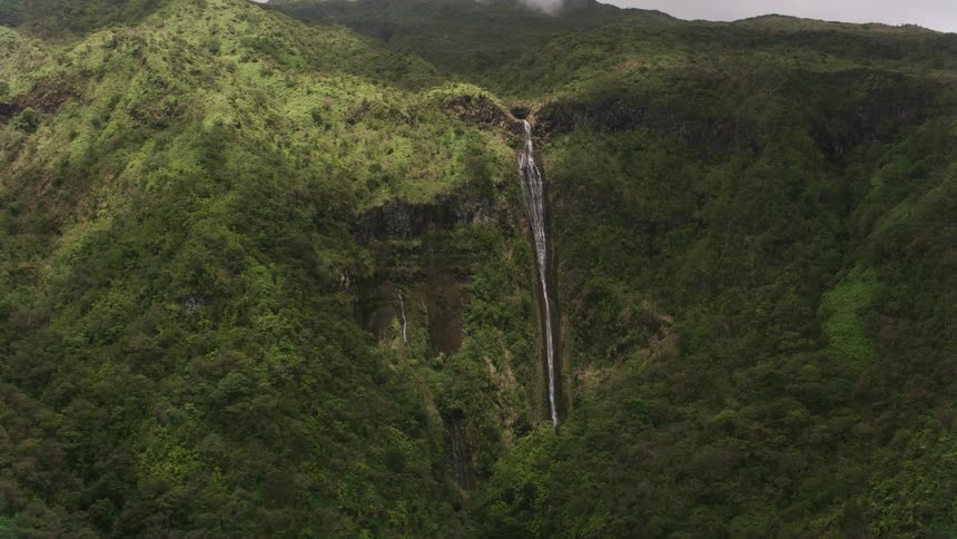 A mountain stream flows off a cliff in a waterfall