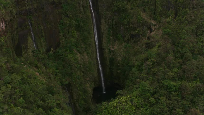 A mountain river flows down off a cliff into a basin