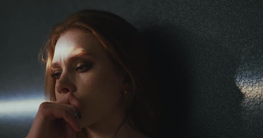 A woman thinks while leaning against a wall