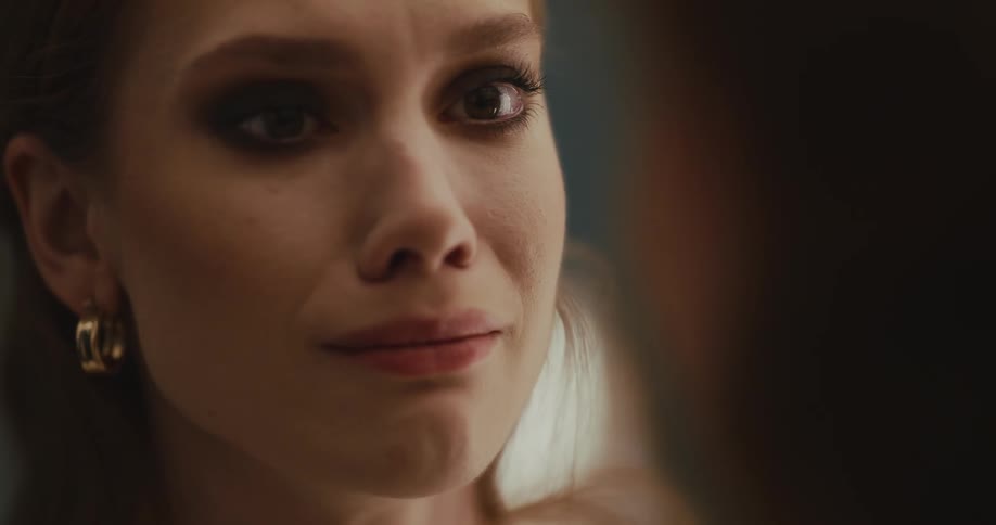 Redheaded woman cries while looking at her reflection in mirror
