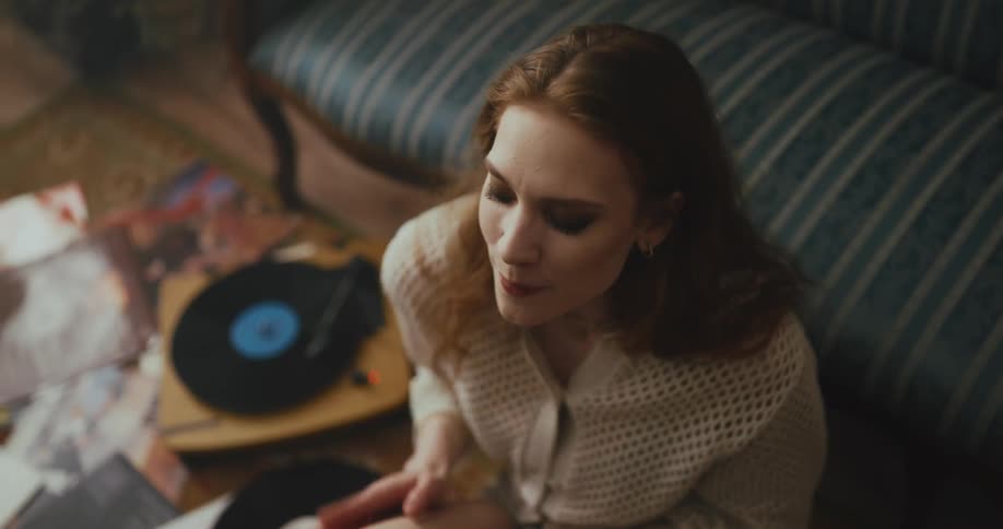 Woman sits on floor grooving as she listens to records