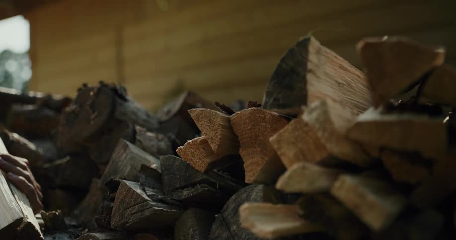 A man stacks firewood outside a house