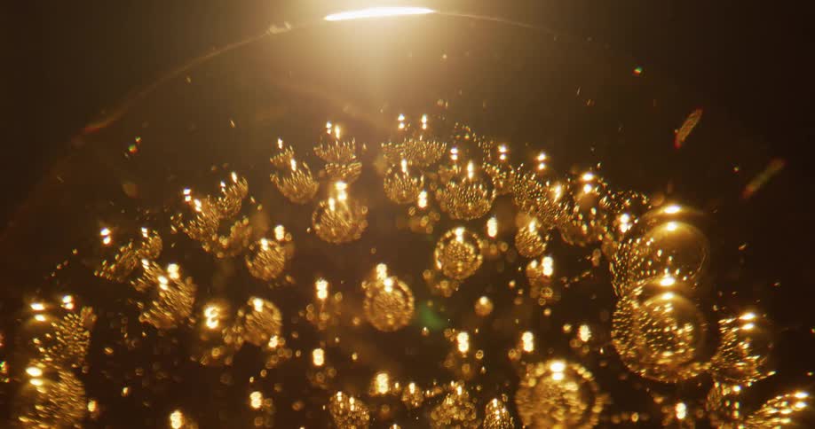 Many small bubbles are trapped within an amber glass sphere that is rotating