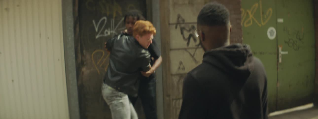 Three men outside one wanting to fight and one holding him back