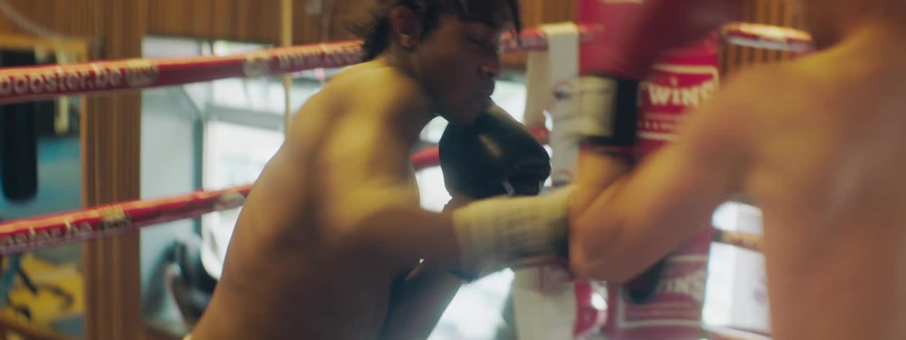 Two men spar in boxing ring in gym