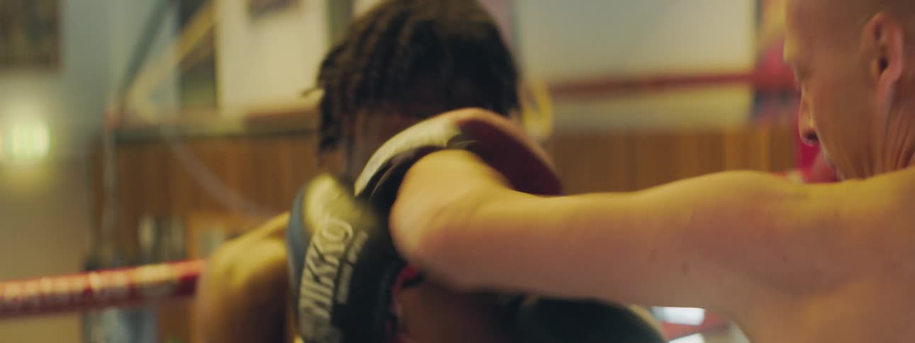 Two black man spar together in a boxing ring