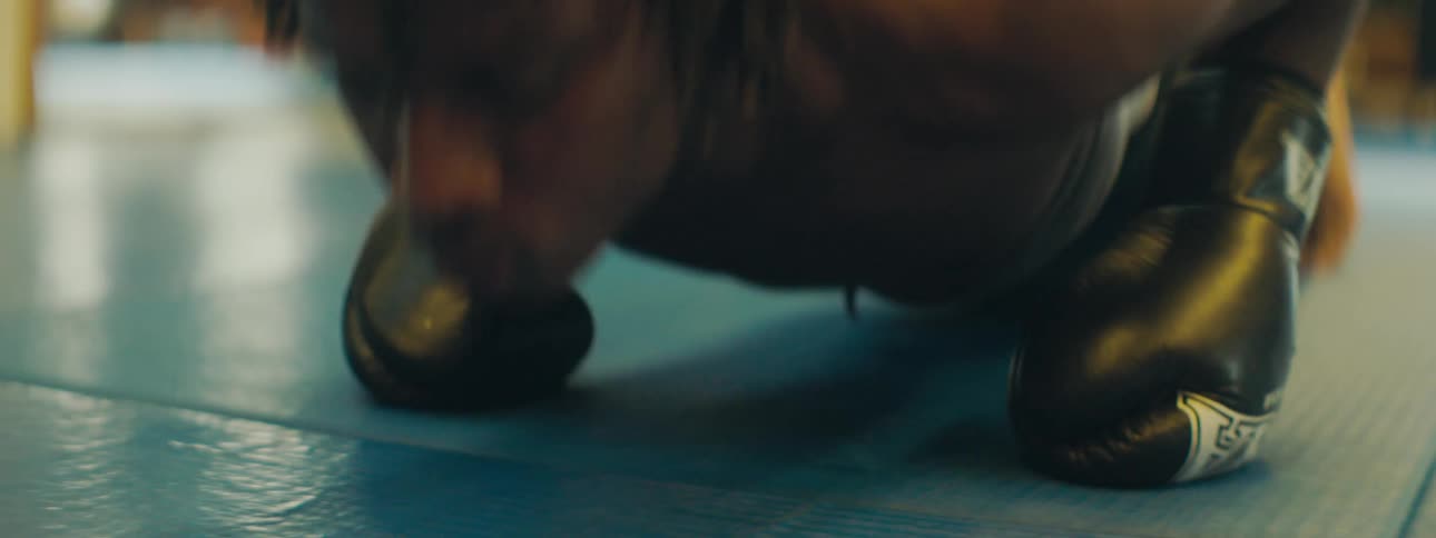 A man with boxing gloves doing push ups