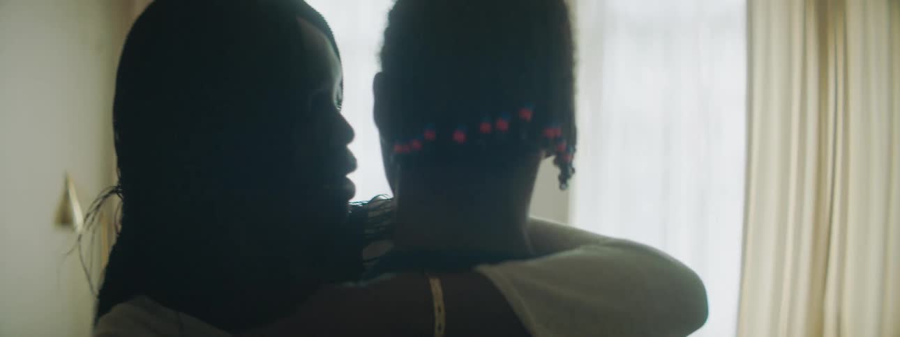A teenage girl hugs a boy close to her and talks to him and gives him a kiss