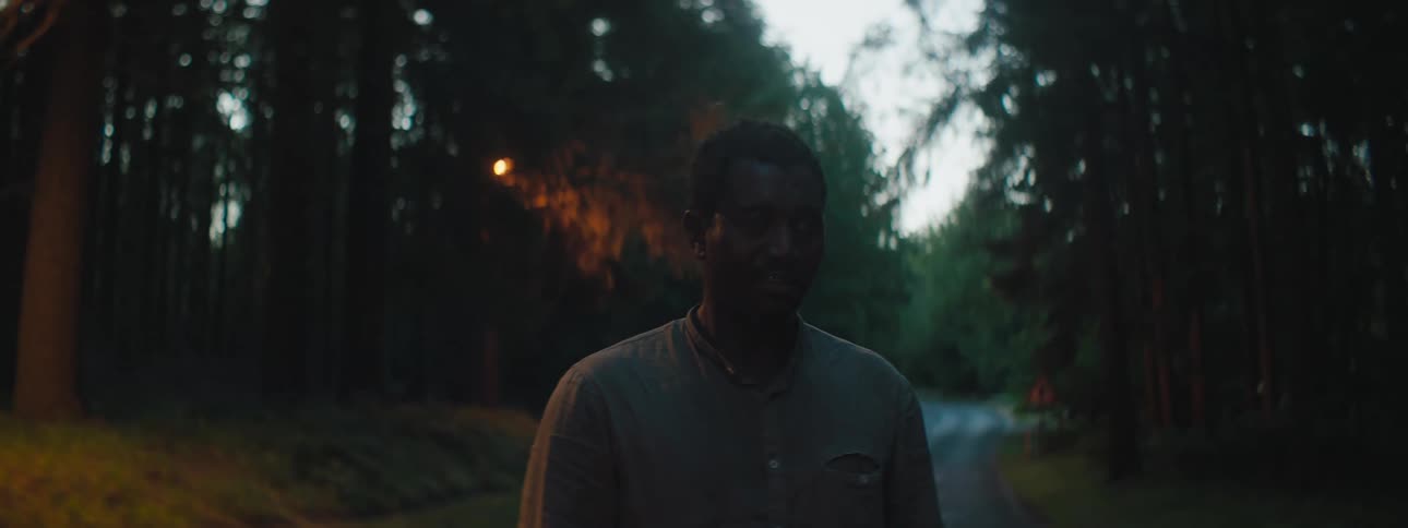 A man standing on a road next to a forest