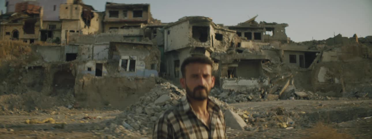 A man standing with dilapidated buildings and the sky and clouds in the background