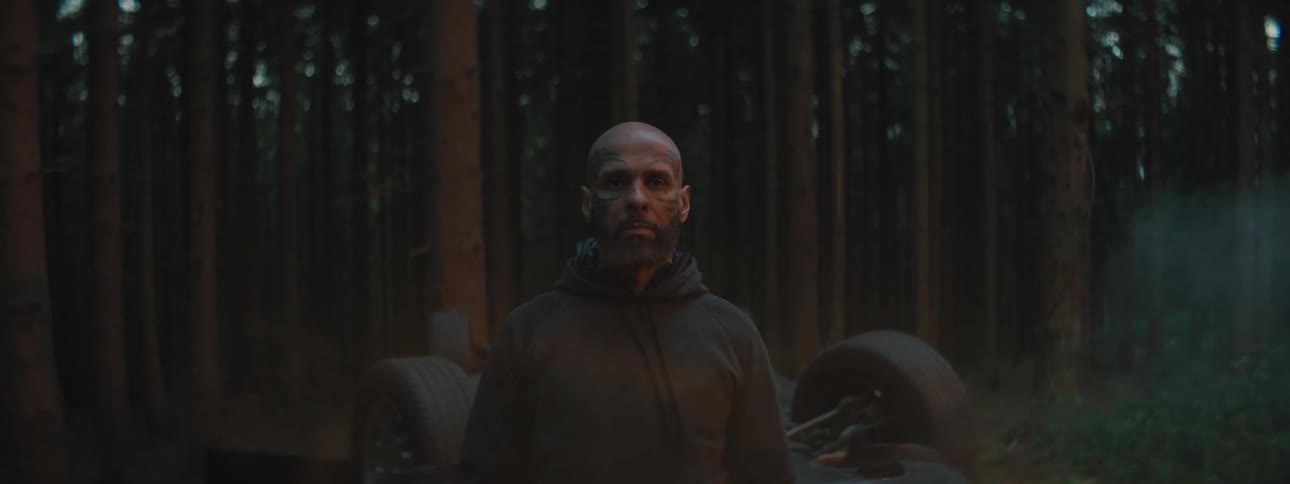 A man stands in the forest with a crashed vehicle
