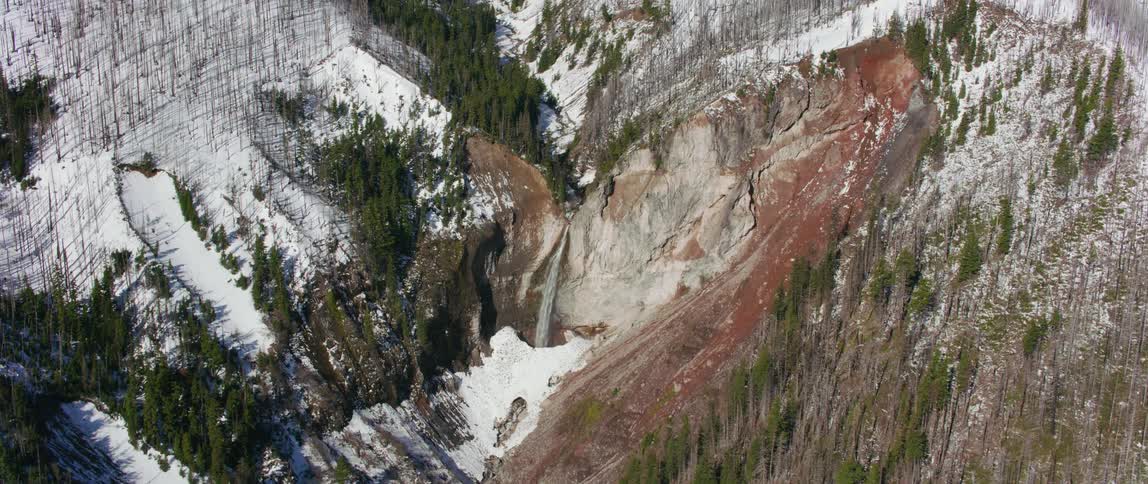 A waterfall rushing in to a river in a mountain range