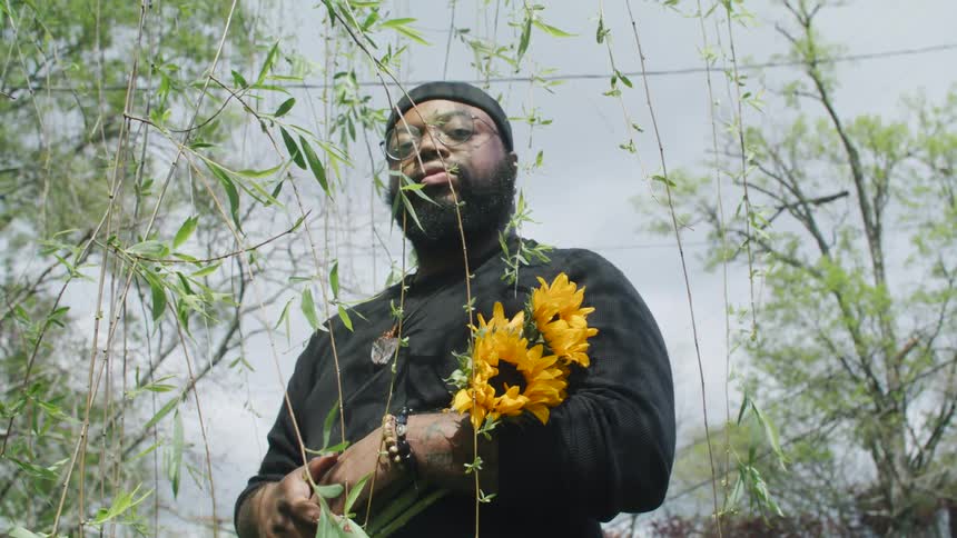 A man stands outside holding a bouquet of flowers