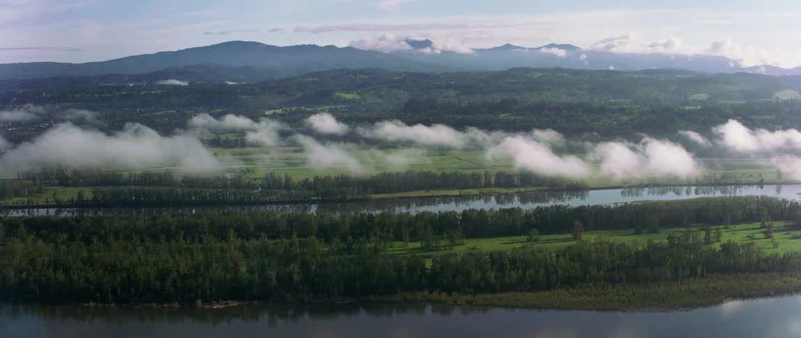 Clouds moving over a river with a mountain range in the distance