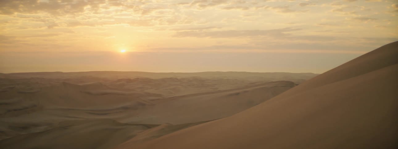 The sun setting over sand dunes in a remote desert