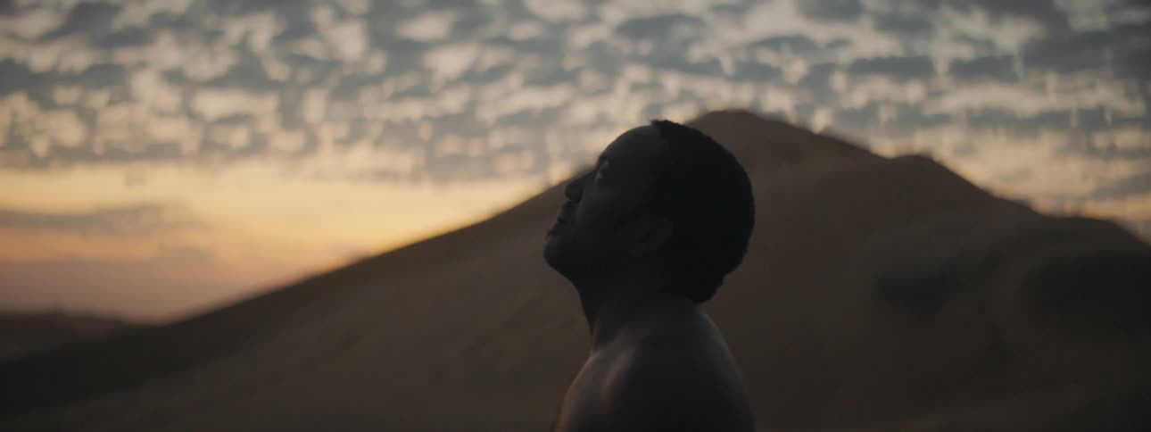 A man is standing outdoors at dusk