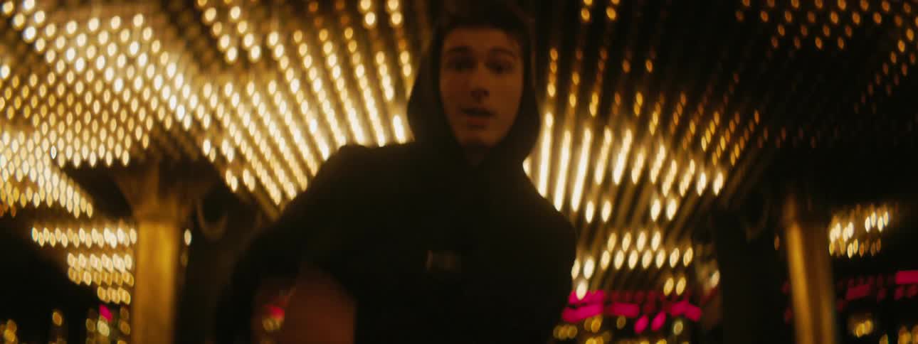 A man in a hoodie dances under a ceiling covered in a flashing light array