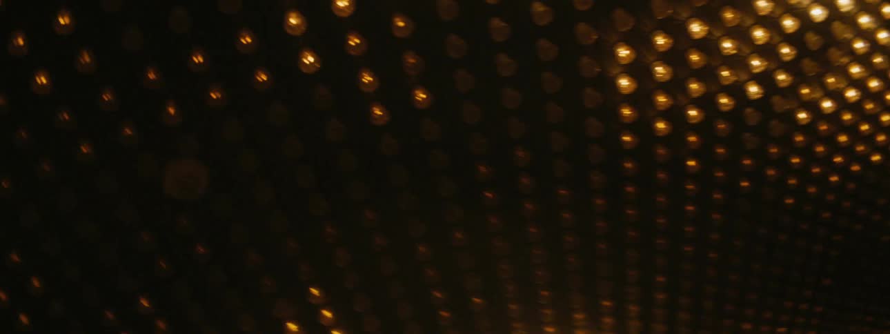 Gold columns support ceiling full of light bulbs that brighten and darken in patterns