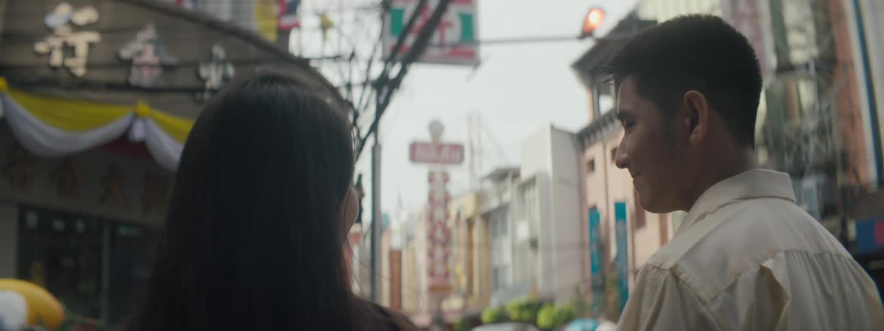 A man and woman smile at each other as they walk through a busy city