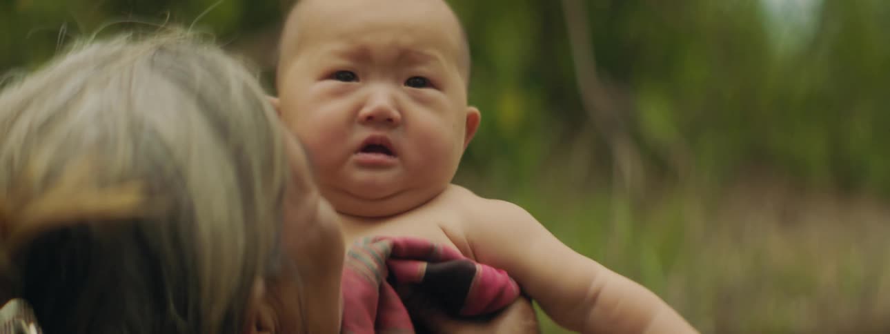 A woman bounces her grandson up and down as they stand outside