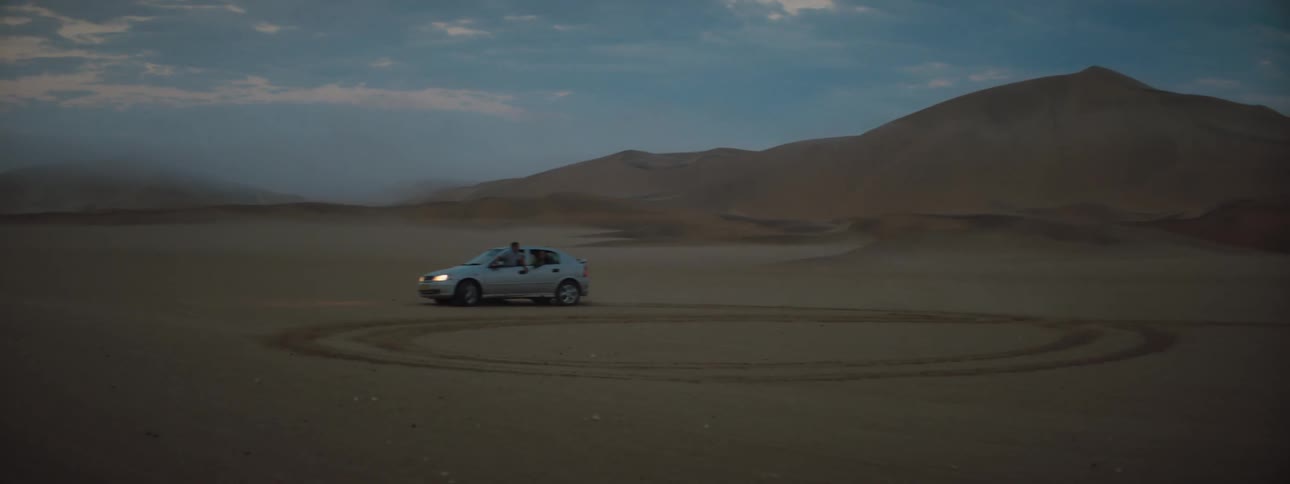 Car driving in circles in the desert at dusk
