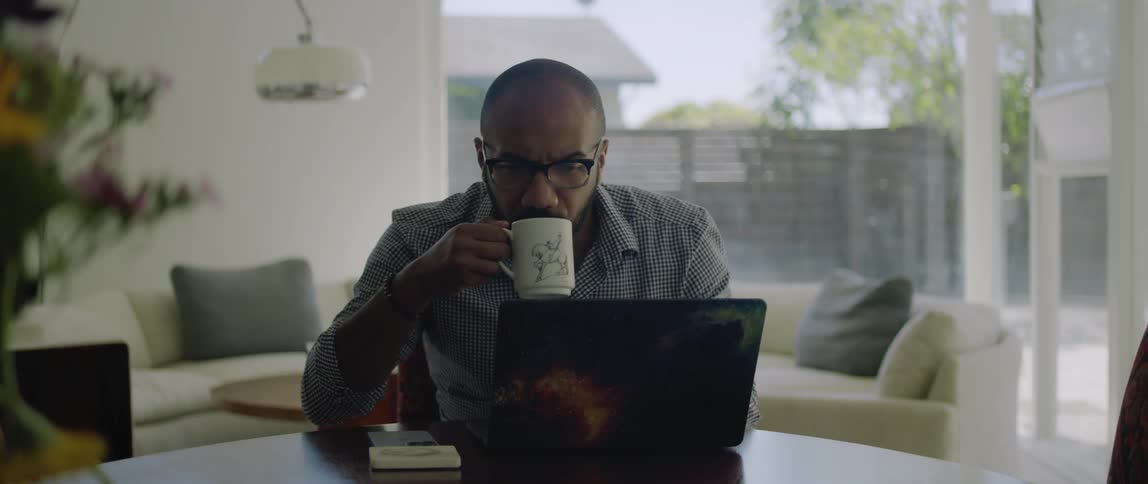 A man using a laptop and sipping coffee
