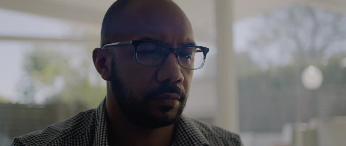 A man wearing glasses blinks a few times as he focuses on his computer
