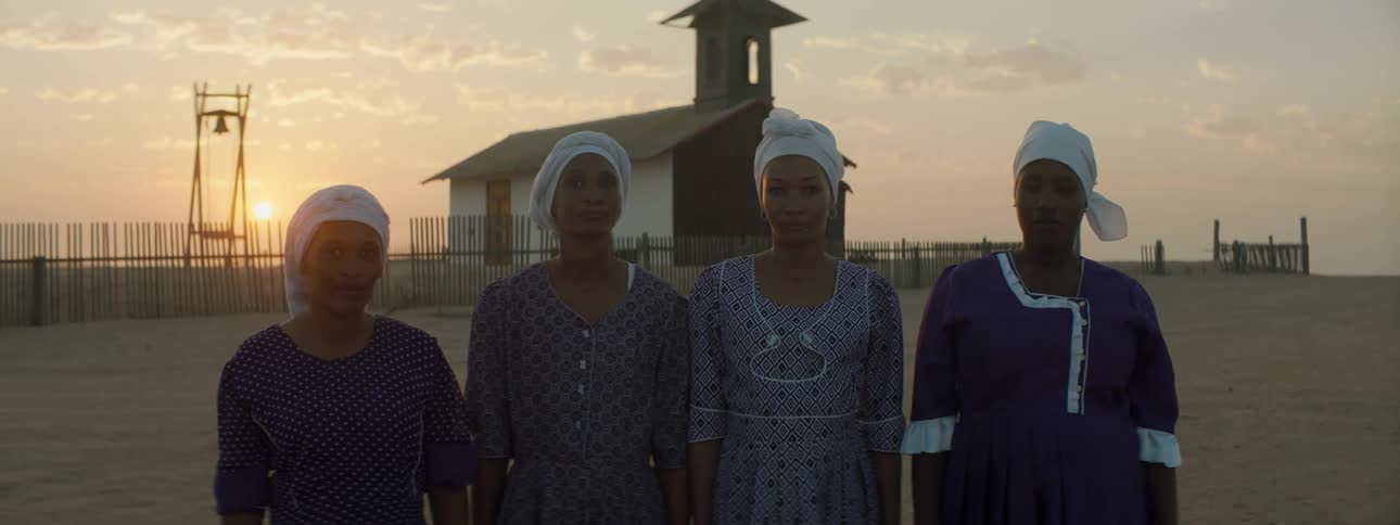 Four women standing in front of a building in a rural area