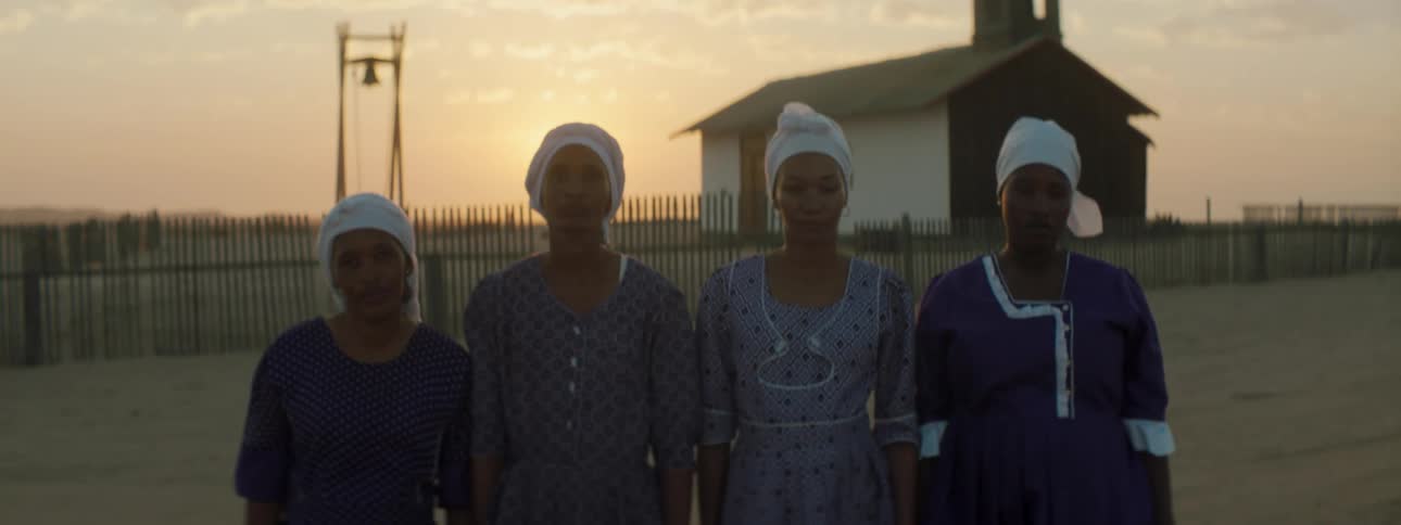 Four women standing in front of a building in a rural area
