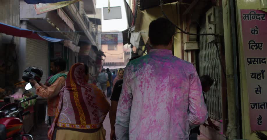 A man walks through a narrow alley in an Indian city during the day