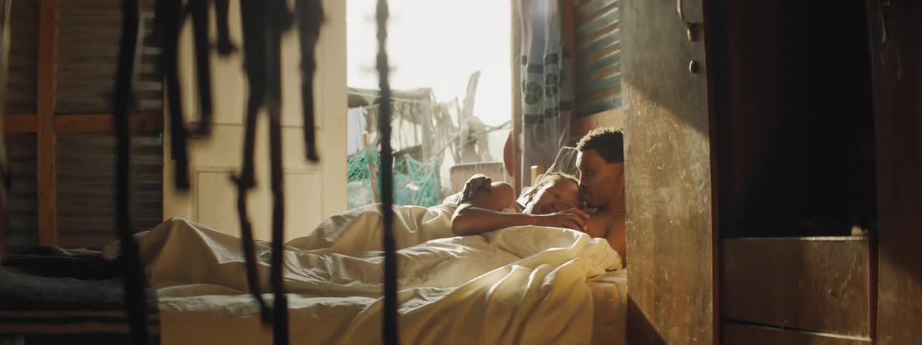 Couple laying in bed under sheets cuddled up together