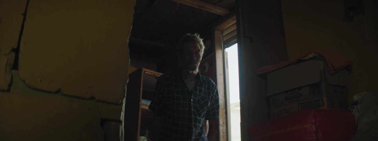 An older man standing inside a doorway and looks outside