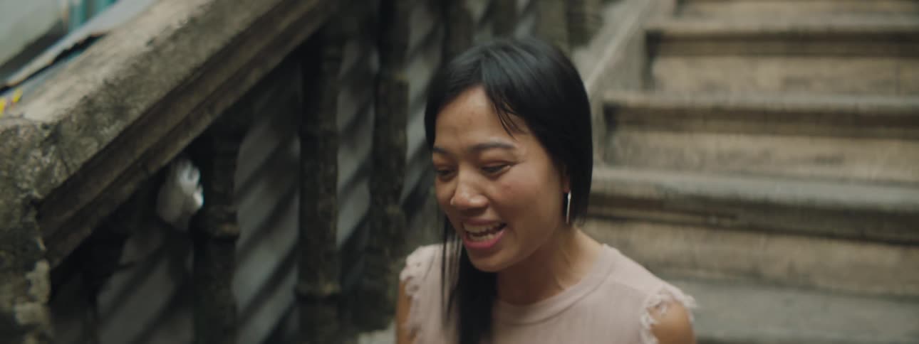 A woman is sitting on a set of stairs singing clapping and smiling