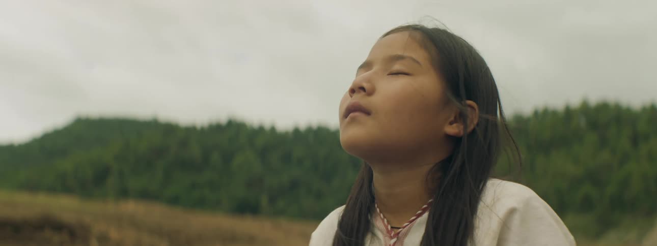 Girl with straight hair and white sweatshirt looks up at the sky with eyes closed