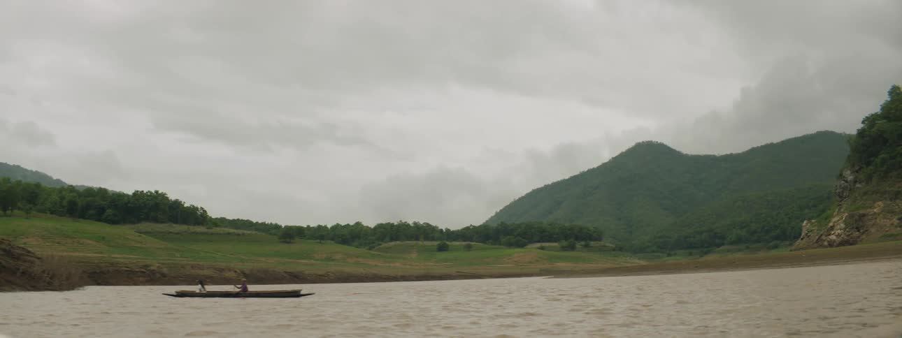 Two people boating on a lake on a cloudy summer day