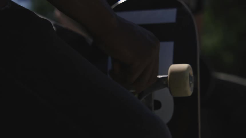 A man tightens wheels on a skateboard