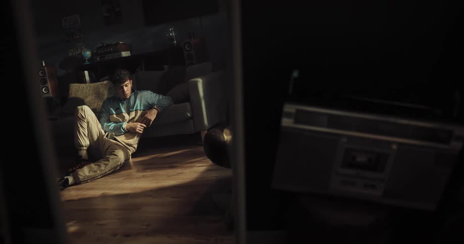 A man breathes deeply while sitting on the floor of a dimly lit living room during the day