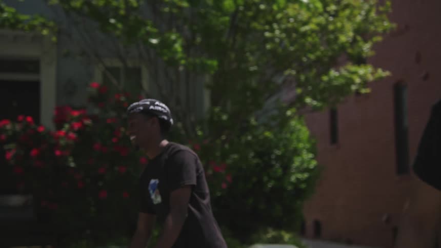 Two people are moving down the street that has a lot of trees