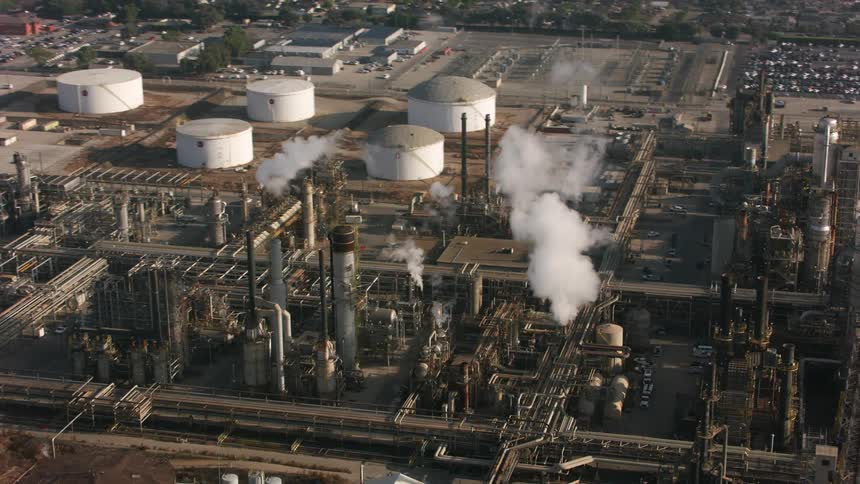 White smoke or steam coming out of a chimney on a factory or refinery on a small town