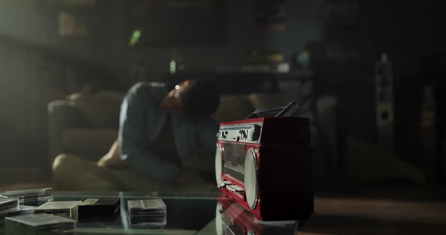 A man does stretches on the floor of a dimly lit living room during the day