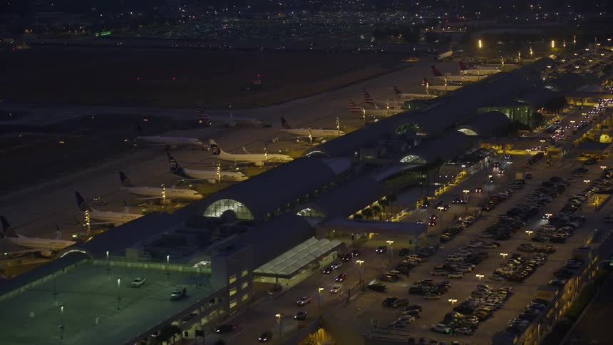 Traffic travels along a road in front of an airport at night